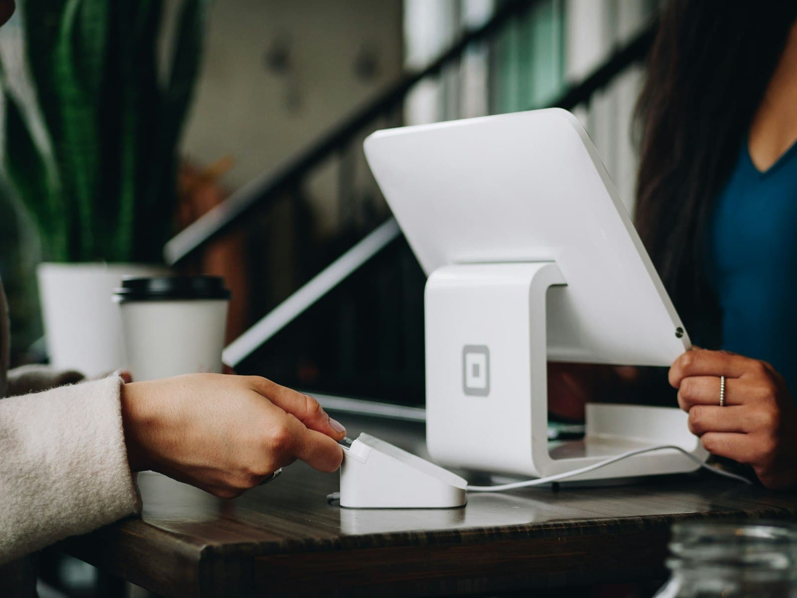 Customer tapping a card at a countertop payment terminal in a cafe