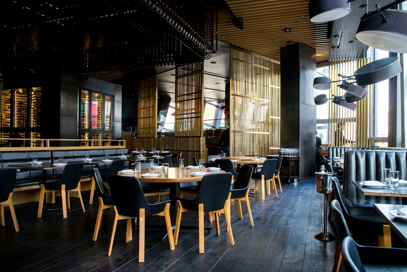 Empty restaurant dining room with leather booths, wooden chairs, and set tables