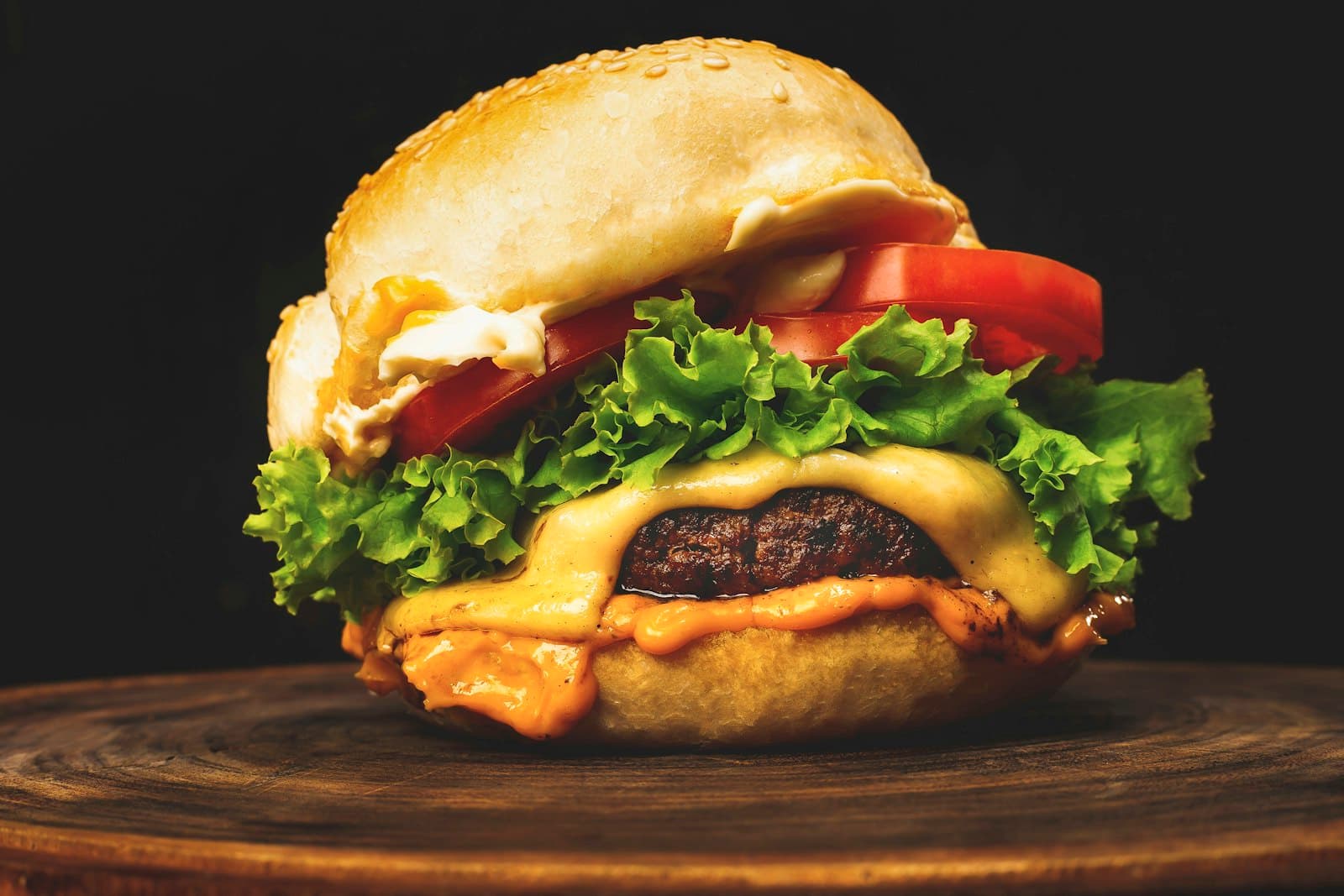 A cheeseburger with lettuce and tomato on a wooden board