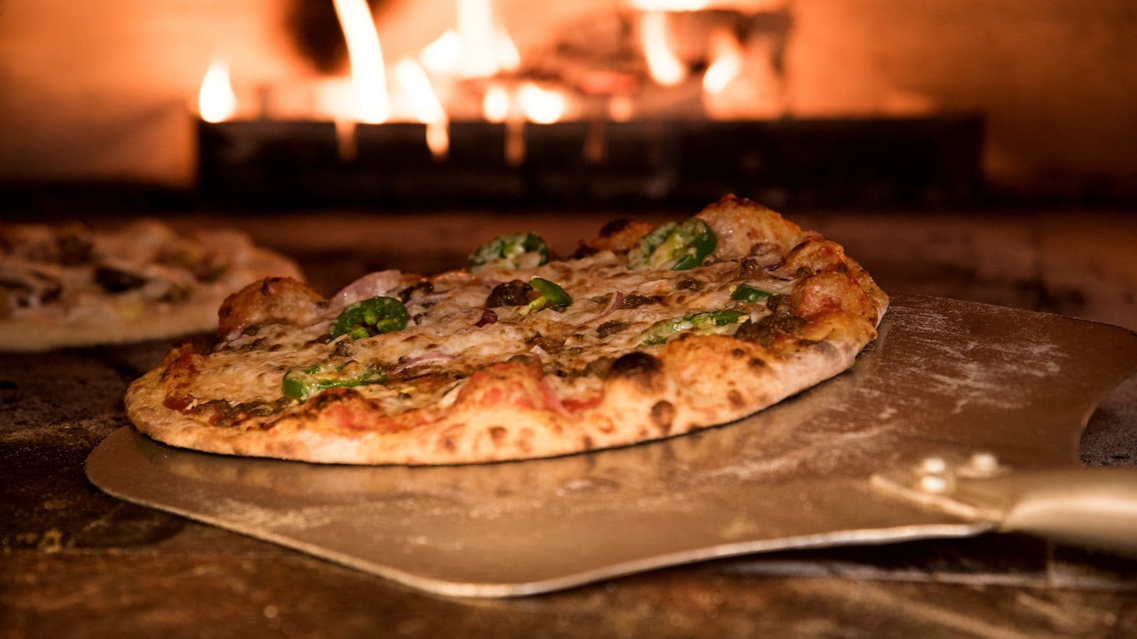 Pizza coming out of a wood-fired oven, the modeled Bella's Trattoria archetype this twelve-month switch is built around