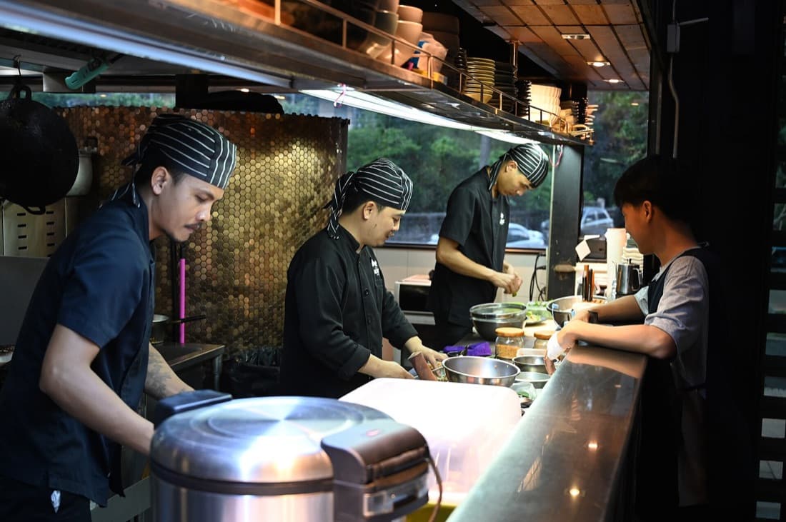 A busy line behind the counter while a customer waits: every order source lands here
