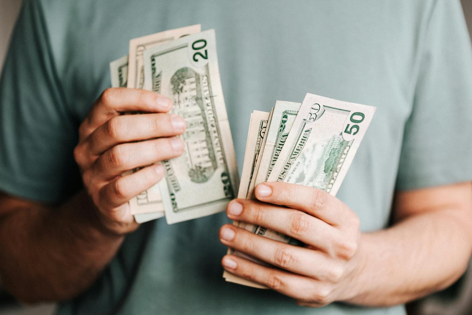 A person counting a handful of twenty and fifty dollar bills