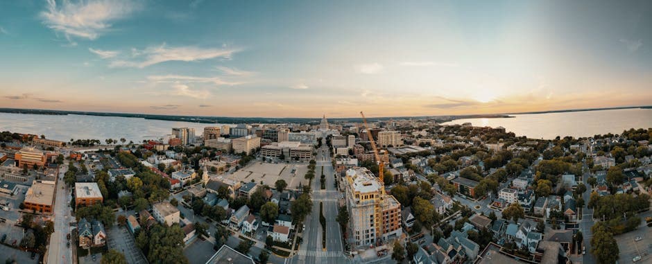 Madison, Wisconsin, looking across the isthmus from above, with the Wisconsin State Capitol dome anchoring the center of the city and Lake Mendota and Lake Monona framing the urban corridor on either side.