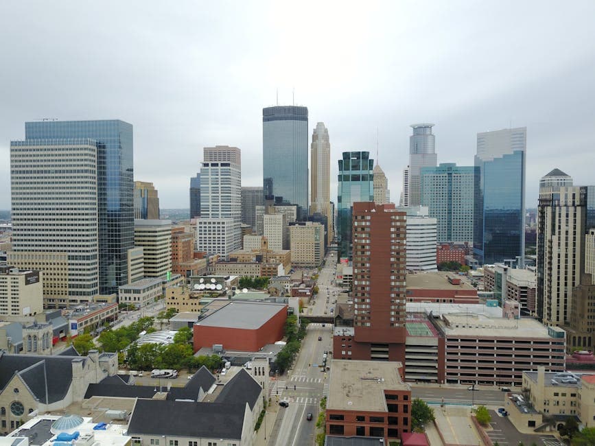 Minneapolis skyline along the Mississippi River, with the Stone Arch Bridge and the Mill District visible in the foreground at dusk.