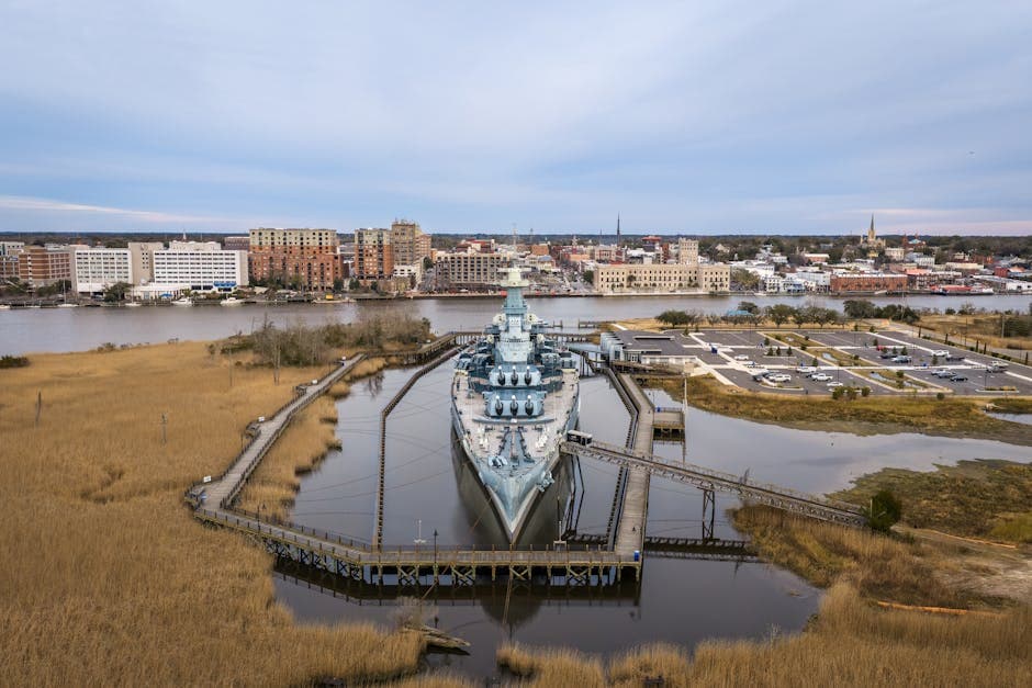 Wilmington NC riverwalk along the Cape Fear River with the historic district to the east and the USS North Carolina battleship moored on the west bank